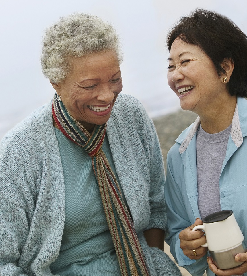 Two cheerful middle aged female friends talking on the beach Image